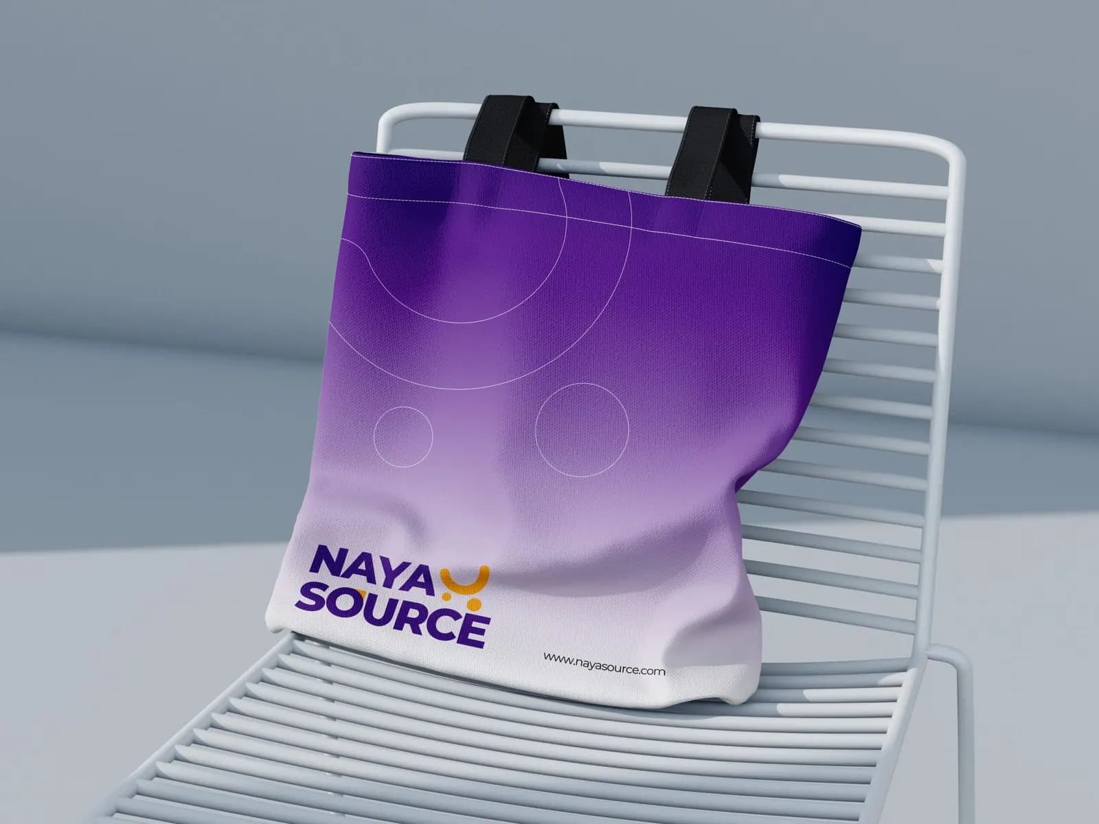 NayaSource tote bag printed with the logo on a purple gradient, resting on a metal chair
